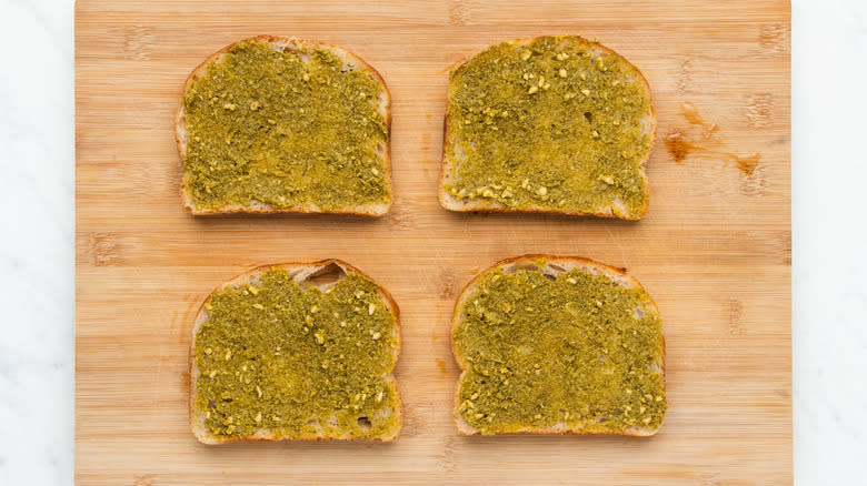 Pesto covered bread slices on board