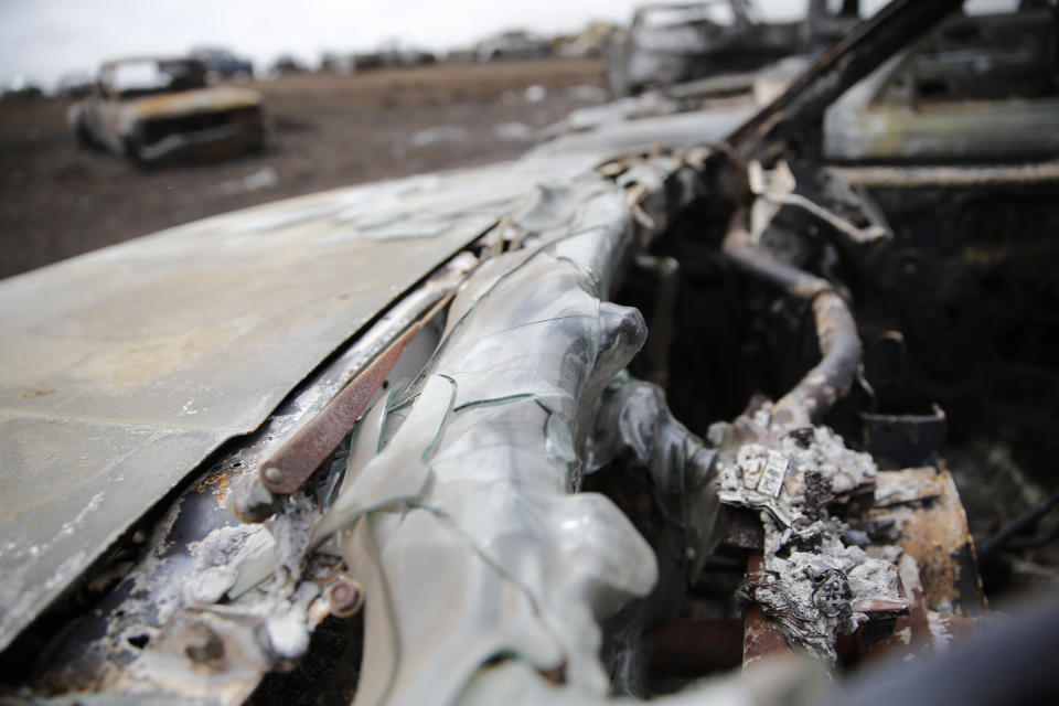 A truck destroyed by fire sits on Joshua Kihe's property near Waimea, Hawaii, Wednesday, Aug. 4, 2021. The area was scorched by the state's largest-ever wildfire. (AP Photo/Caleb Jones)