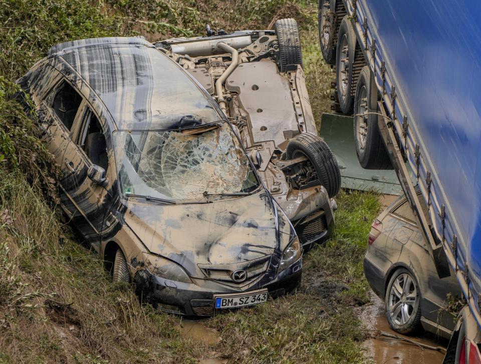 Two cars are next to a truck while another is under it on a road in Erftstadt, Germany, Saturday, July 17, 2021. Due to strong rain falls the small Erft river went over the banks causing massive damages. (AP Photo/Michael Probst)