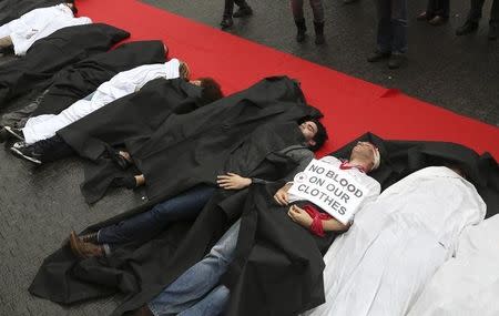 Activists stage a protest acting out a scene where actors portraying as victims, lie along a red carpet in a shopping district in central Brussels, to mark the first anniversary of the Rana Plaza factory collapse April 24, 2014. REUTERS/Francois Lenoir