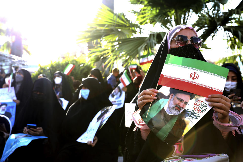 A supporter of presidential candidate Ebrahim Raisi holds a sign and the Iranian flag during a rally in Tehran, Iran, Wednesday, June 16, 2021. Iran's clerical vetting committee has allowed just seven candidates for the Friday, June 18, ballot, nixing prominent reformists and key allies of President Hassan Rouhani. The presumed front-runner has become Ebrahim Raisi, the country's hard-line judiciary chief who is closely aligned with Supreme Leader Ayatollah Ali Khamenei. (AP Photo/Ebrahim Noroozi)