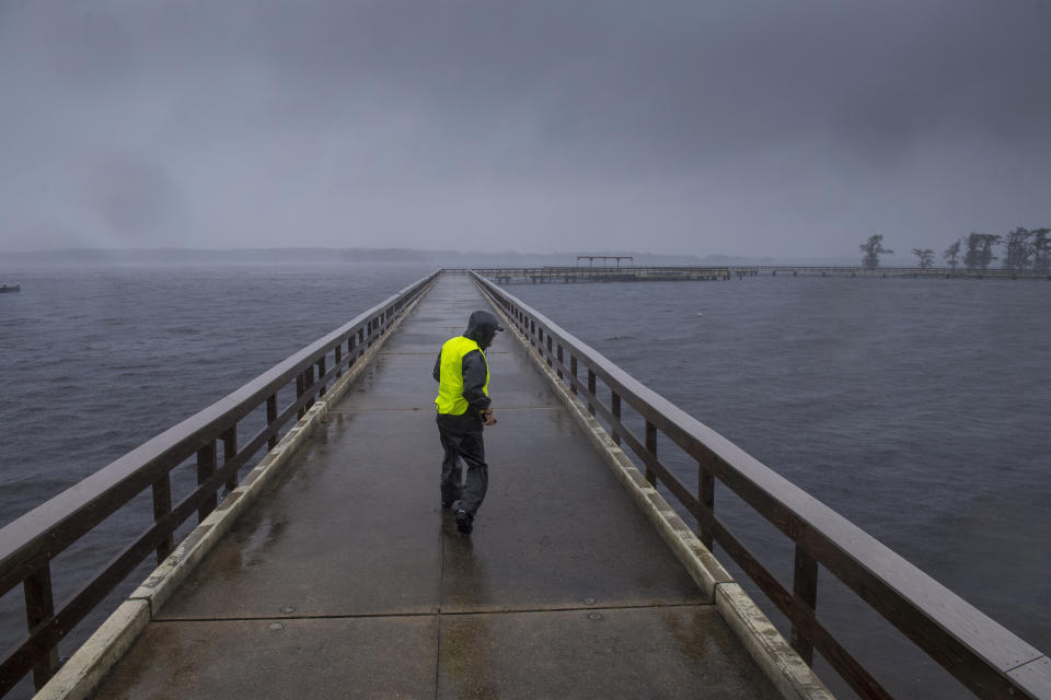 Storm chaser Shaun Piegdon walks down a pier over Lake Arthur as Hurricane Delta's outer bands move into Louisiana, Friday, Oct. 9, 2020. Residents in south Louisiana braced to relive a nightmare Friday as bands of rain from approaching Hurricane Delta began soaking the same area of the state that was badly battered by a deadly hurricane six weeks ago. (Chris Granger/The Advocate via AP)