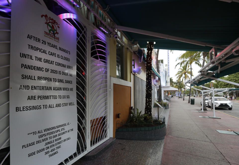 A sign is shown outside the closed Mango's Tropical Cafe along the normally bustling streets of the Art Deco district, Wednesday, March 25, 2020, in Miami Beach, Florida's famed South Beach. The new coronavirus causes mild or moderate symptoms for most people, but for some, especially older adults and people with existing health problems, it can cause more severe illness or death.(AP Photo/Wilfredo Lee)