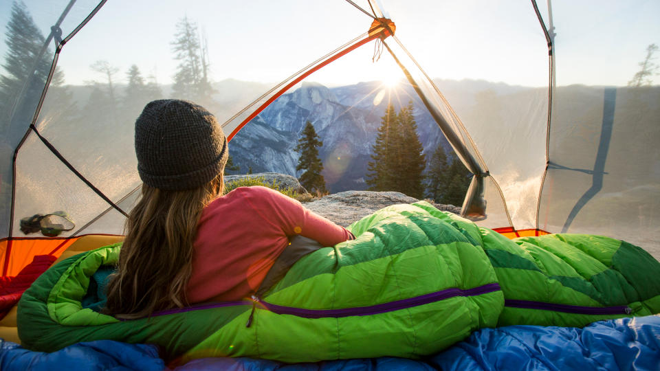 sleeping bag temperature: camper looking out at dawn