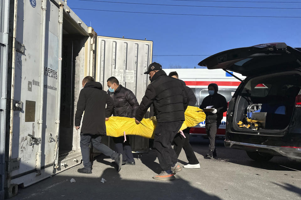 CORRECTS TO DELETE THE ERRONEOUS FACT OF THE NUMBER OF THE DEATHS IN 2023 - FILE - Workers transfer a body into a container for storage at a crematorium after a surge in deaths in Beijing on Dec. 17, 2022. China's population dropped by 2 million people in 2023 in the second straight annual drop as births fell and deaths jumped after the lifting of COVID-19 restrictions, the government said Wednesday. (AP Photo/Ng Han Guan, File)