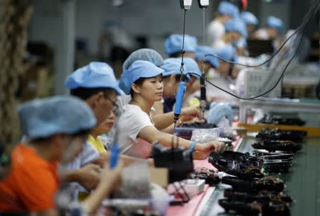 Employees work on the production line of a robot vacuum cleaner at a factory of Matsutek in Shenzhen