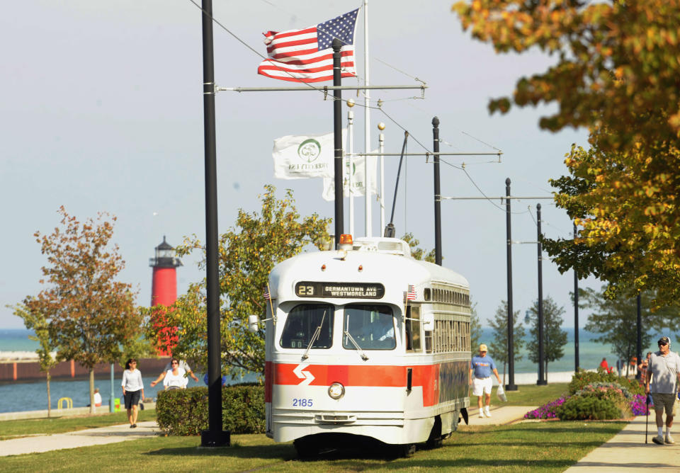 In this Sept. 28, 2013 photo, the Southeastern Pennsylvania streetcar heads west parallel and next to 54th Street during Kenosha Streetcar Day in Kenosha, Wis. When the city of Kenosha lost the auto plant that employed thousands, the a bruised community in southern Wisconsin plucked something unexpected from its pre-automobile past to help reinvent the city and fill its depressed downtown with life. They brought back their street cars, sending brightly colored antique trolleys creeping along a two-mile loop around the city and along the lake Michigan shore. (AP Photo/Michael Schmidt)