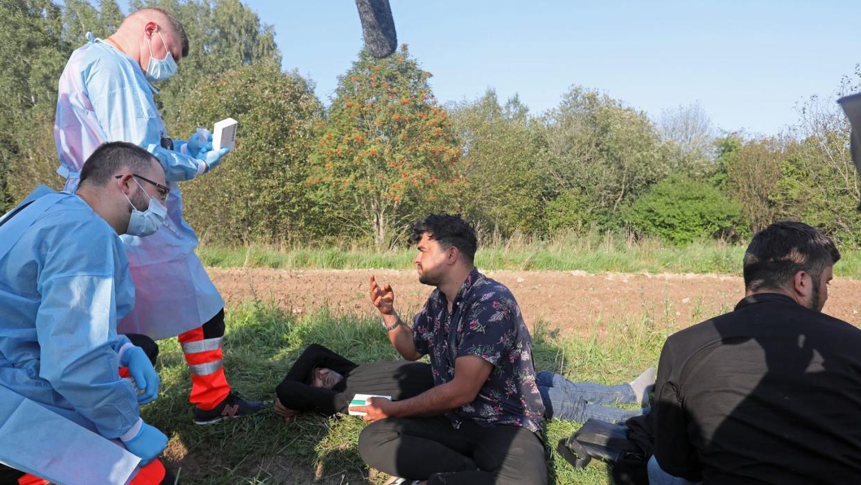 Sanitäter sprechen mit der Gruppe von Flüchtlingen an der polnisch-belarussischen Grenze.