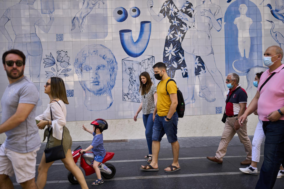 People walk along a street in Madrid, Spain, Saturday, June 26, 2021. Almost a year after face masks became mandatory indoors and outdoors in Spain, people from Saturday are no longer required to wear them outside as long as they can stay at least 1.5 meters (5 feet) apart.(AP Photo/Manu Fernandez)