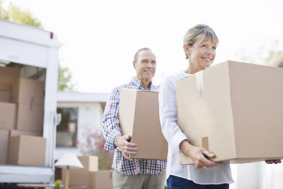 Senior couple carrying moving boxes.