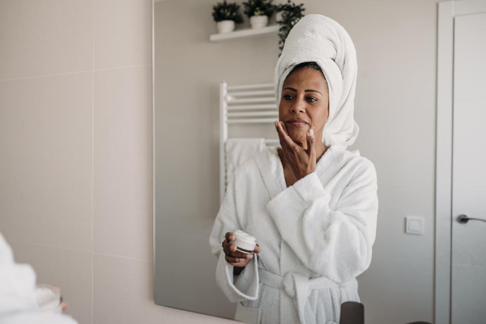 Mature woman applying morning skin care routine in mirror