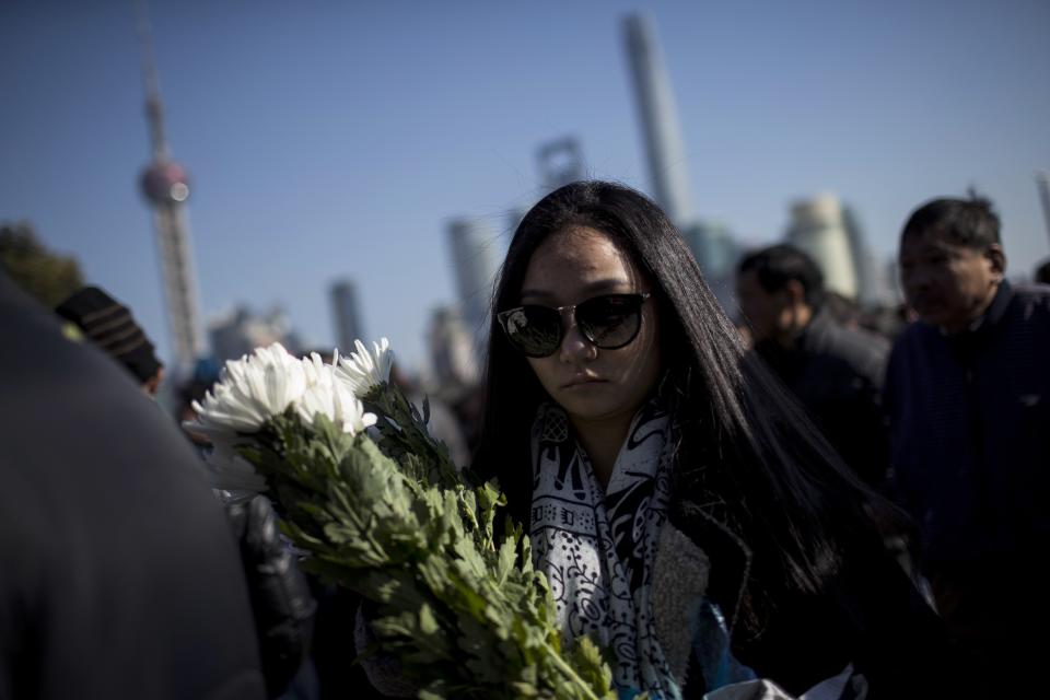 A woman offers flowers during a memorial ceremony in memory of people who were killed in a stampede incident during a New Year's celebration, on the Bund in Shanghai