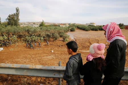 People watch civil defense members as they look for missing persons after rain storms unleashed flash floods, in Madaba city, near Amman, Jordan, November 10, 2018. REUTERS/Muhammad Hamed