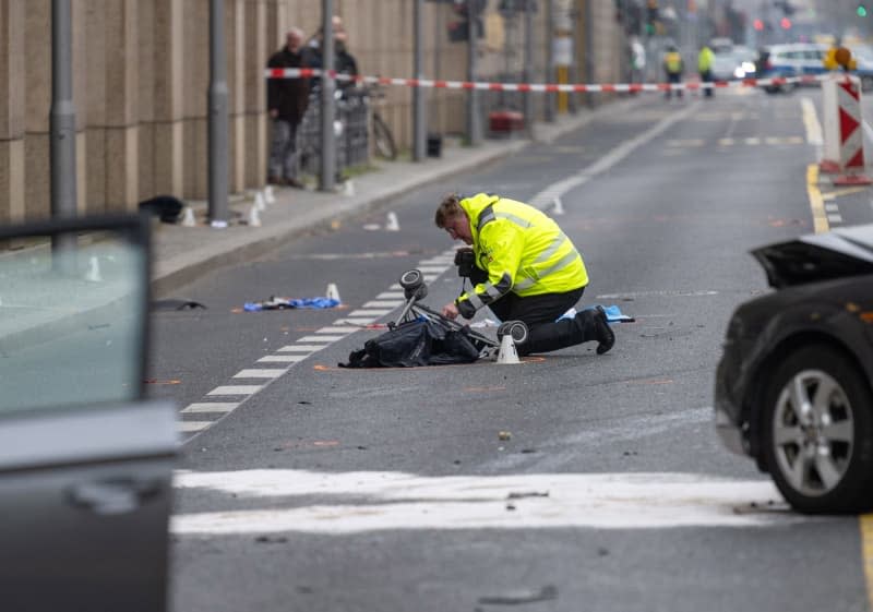 A police officer kneels by a baby carriage at the scene of an accident in Leipziger Strasse. Four people, including a mother and her child, were seriously injured in the serious accident in Berlin-Mitte. Christophe Gateau/dpa