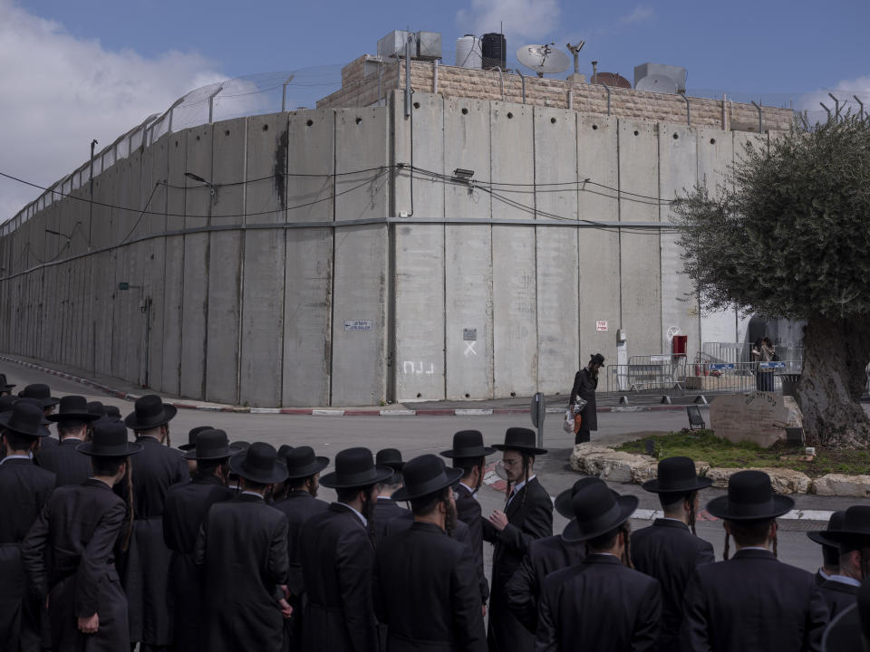 FILE - Ultra Orthodox Jews wait for transportation next to the concrete separation barrier built by Israel to secure the Rachel's Tomb Judaism's third holiest shrine, in the West Bank town of Bethlehem, March 4, 2022. (AP Photo/Oded Balilty, File)