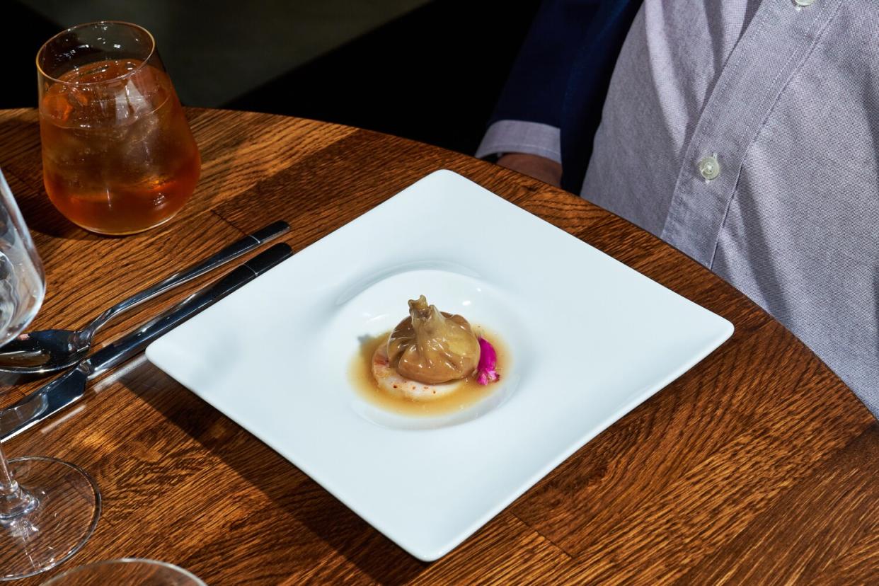 A purse-like dumpling on a white dinner plate.