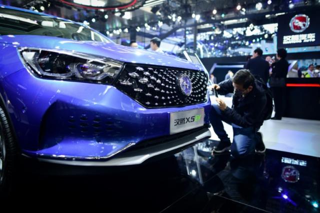 A man takes a photo of Hanteng X5 EV car at the Beijing auto show