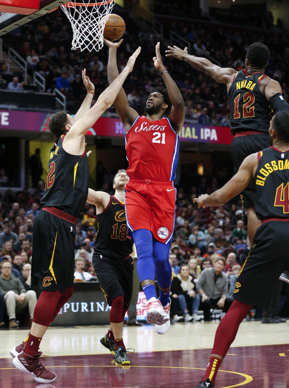 Philadelphia 76ers' Joel Embiid (21), from Cameroon, shoots against Cleveland Cavaliers' Larry Nance Jr. (22), David Nwaba (12), and Jaron Blossomgame (4) during the second half of an NBA basketball game Sunday, Dec. 16, 2018, in Cleveland. (AP Photo/Ron Schwane)