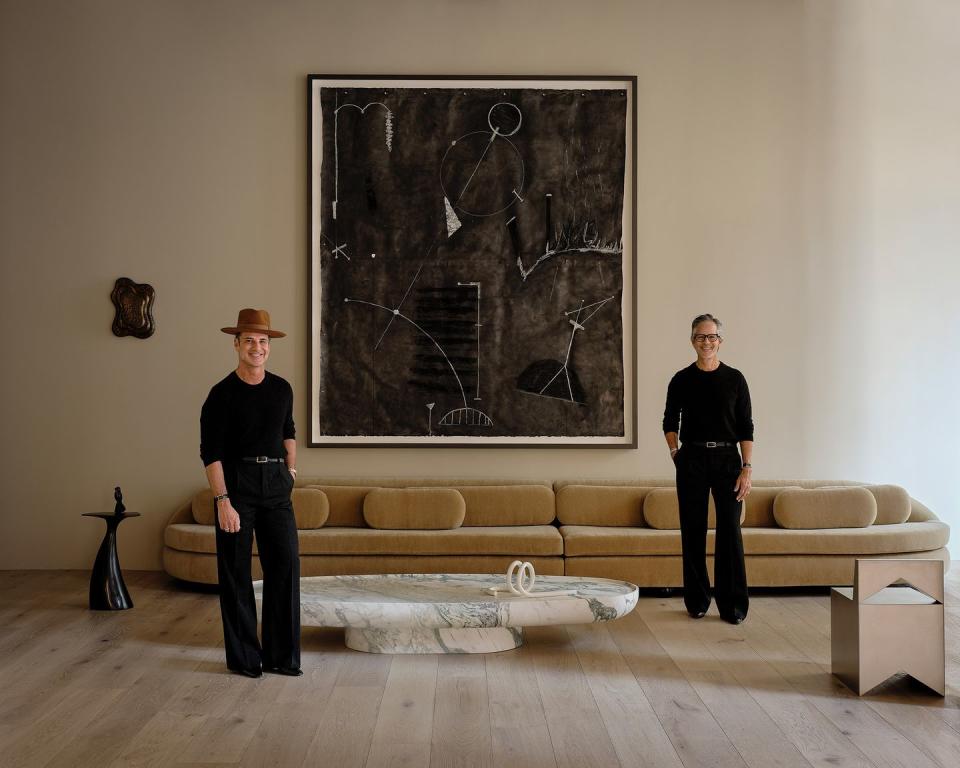 a couple of men standing in front of a large painting