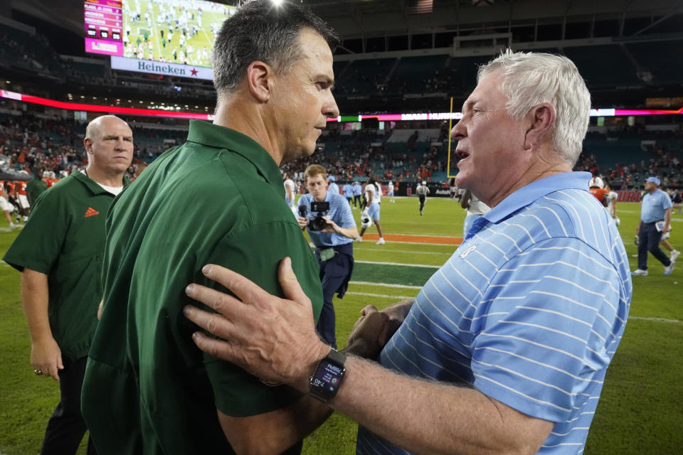 Miami head coach Mario Cristobal, left, and North Carolina head coach Mack Brown meet after North Carolina beat Miami 27-24 on Saturday, Oct. 8, 2022, in Miami Gardens, Fla. (AP Photo/Wilfredo Lee)