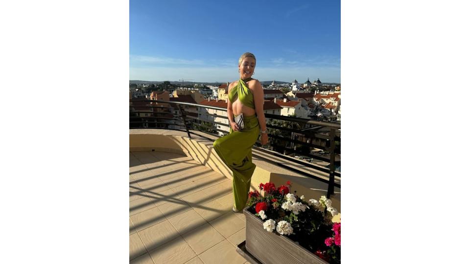 woman wearing green jumpsuit whilst posing on balcony