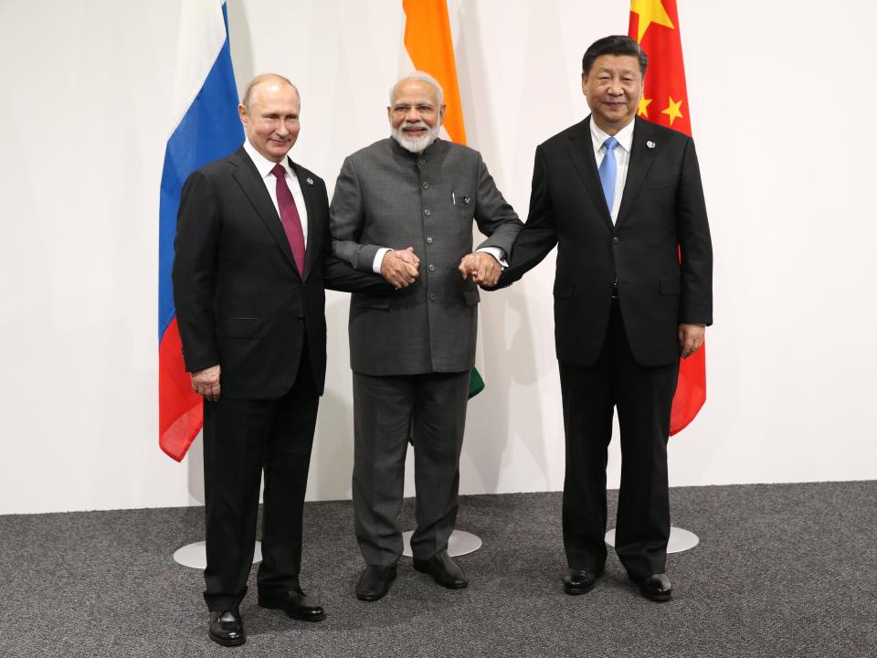 Russian President Vladimir Putin (L), Indian Prime Minister Narendra Modi (C) and Chinese President Xi Jinping (R) in front of respective country flags.