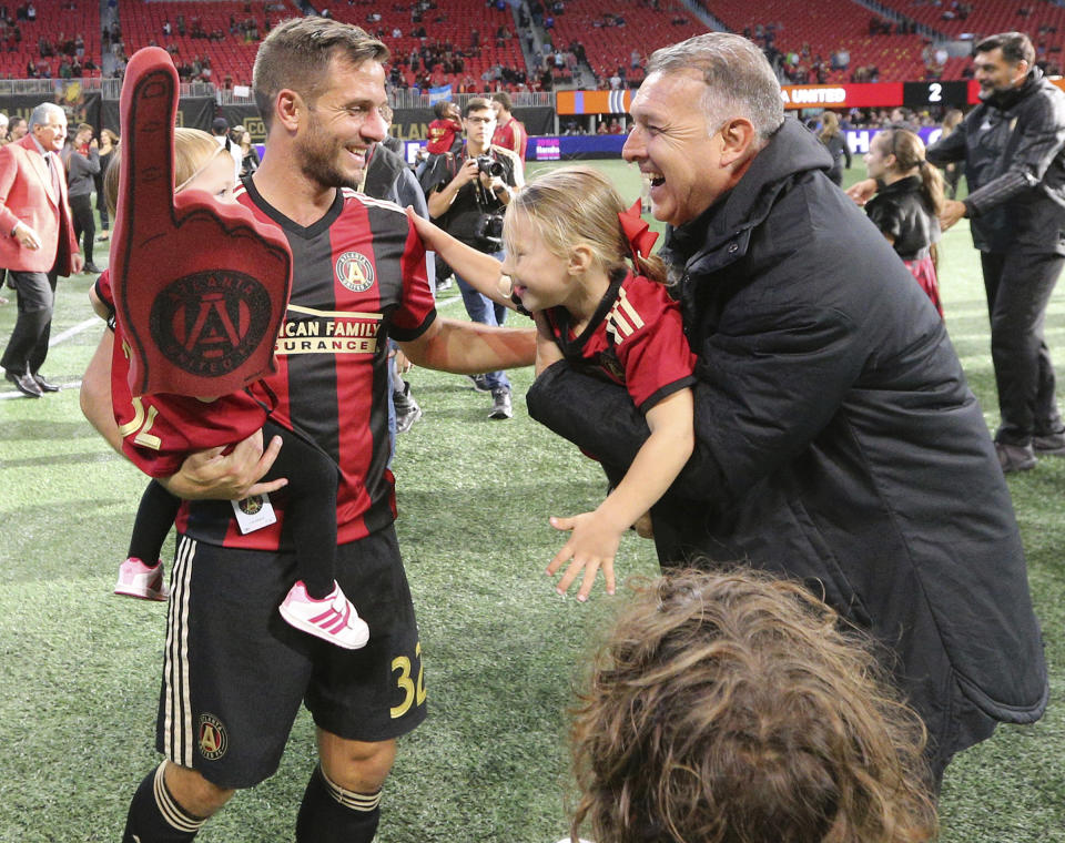 Atlanta United head coach Gerardo Martino, front right, and Kevin Kratz, left, celebrate after clinching a playoff spot with a victory over the Chicago Fire at an MLS soccer match on Sunday, Oct. 21, 2018, in Atlanta. (Curtis Compton/Atlanta Journal-Constitution via AP)