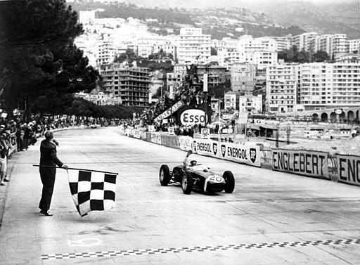 Stirling Moss of Britain raises his hand in victory after passing the finish line in first place at the Monaco Grand Prix Automobile race on May 14, 1961. The checked flag goes down on the circuit in the foreground. Moss is driving a Lotus sports car. (AP Photo)