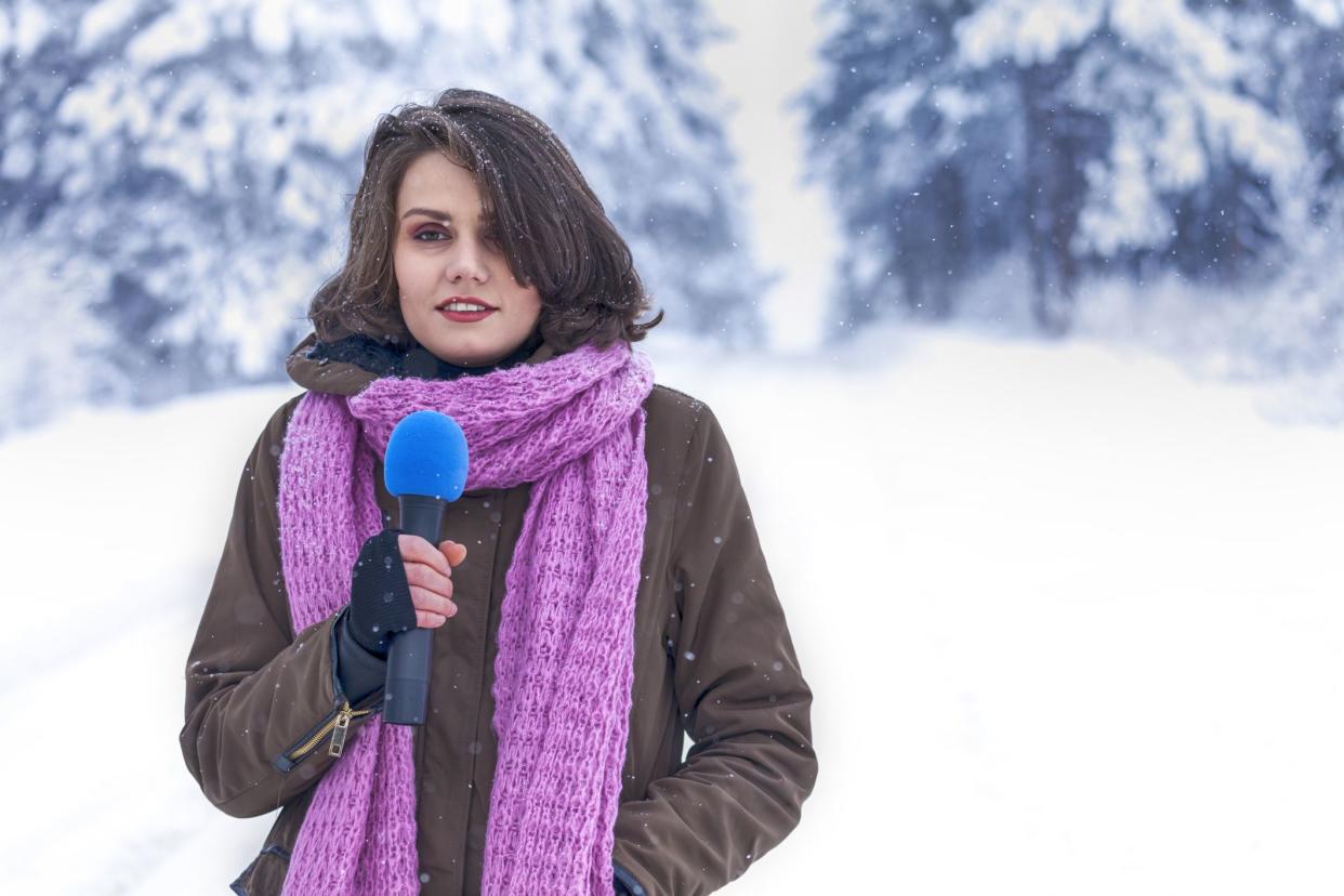 Young television reporterbriadcasting from the winter wood