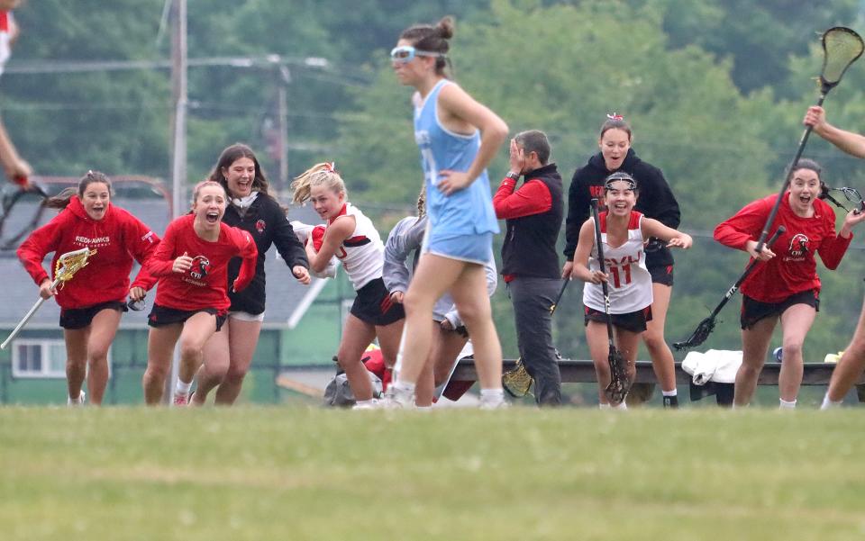 Tucker Pierson (back) sighs relief as the Redhawk bench storms the field as the final whistle blows in their 12-11 girls lacrosse semifinal win over South Burlington in Hinesburg.