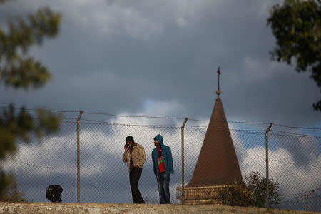 Two men walk next to a fence dividing the Greek and Turkish Cypriots area, on the Turkish Cypriot northern part of the divided city of Nicosia, Cyprus February 16, 2017. REUTERS/Yiannis Kourtoglou