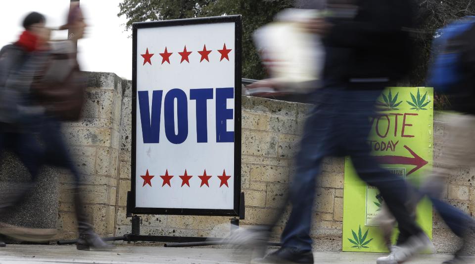 In this Wednesday, Feb. 26, 2014 photo, pedestrians pass voting signs near an early voting polling site, in Austin, Texas. In elections that begin next week, voters in 10 states will be required to present photo identification before casting ballots _ the first major test of voter ID laws after years of legal challenges arguing that the measures are designed to suppress voting. (AP Photo/Eric Gay)