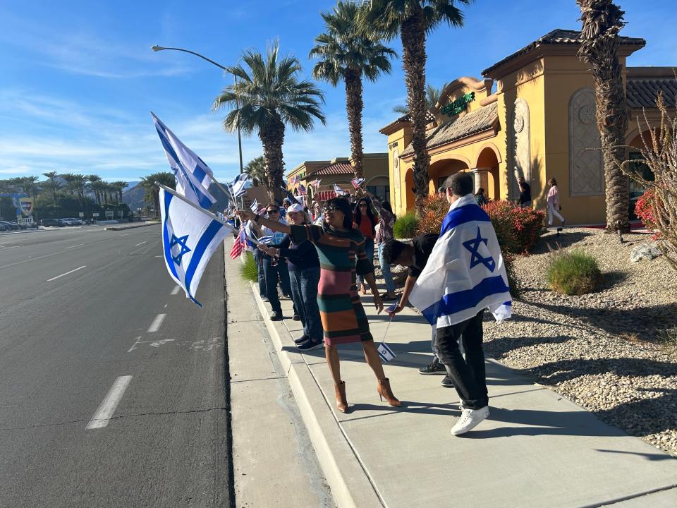 Residents wave flags along Highway 111 in Indio during a pro-Israel rally organized by the local chapter of StandWithUs, an international organization focused on antisemitism and Israel. The rally focused on the release of the remaining hostages held by Hamas.