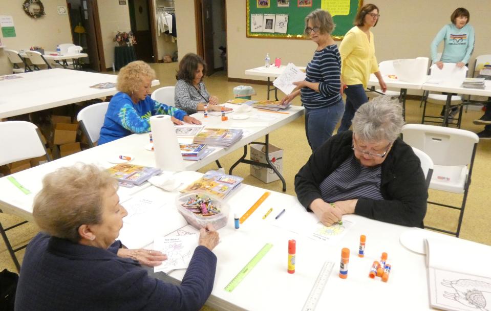 Members of the Bucyrus Salvation Army Women's Auxiliary and other volunteers prepare coloring books for shipment to Ukrainian refugees.