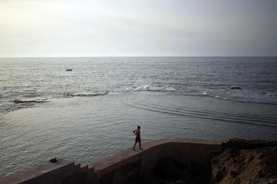 A man walks along a fence before jumping for an evening swim in the Atlantic Ocean, in Rabat, Morocco, Tuesday, Sept. 22, 2020. (AP Photo/Mosa'ab Elshamy)