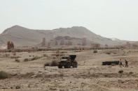 Residents walk near a military truck that belongs to forces loyal to Syria's President Bashar al-Assad, near the historical city of Palmyra May 19, 2015. REUTERS/Stringer