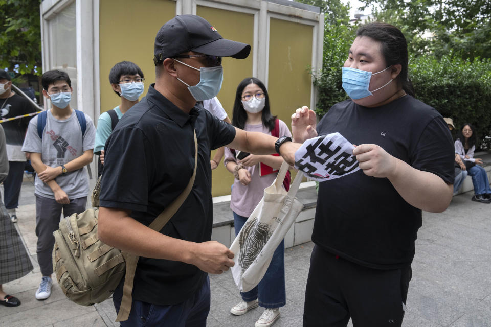 FILE - A man pulls a sign reading "stand together" away from a supporter of Zhou Xiaoxuan, a former intern at China's state broadcaster CCTV, outside a courthouse in Beijing on Sept. 14, 2021. Zhou, who accused well-known state TV host Zhu Jun of groping her when she was an intern and was once praised for her courage in speaking up, faced a campaign of harassment and can no longer post on her public-facing accounts. (AP Photo/Mark Schiefelbein, File)