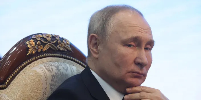 Vladimir Putin holding his hand near his throat