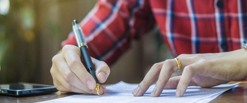 Businessperson Signing Contract,man writing paper at the desk with pen and reading books, Form filling petition agreement of divorce,morning light ,selective focus.copy space