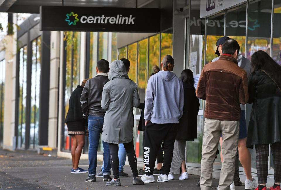 People queue up outside a Centrelink office in Melbourne on April 20, 2020, which delivers a range of government payments and services for retirees, the unemployed, families, carers and parents amongst others. -