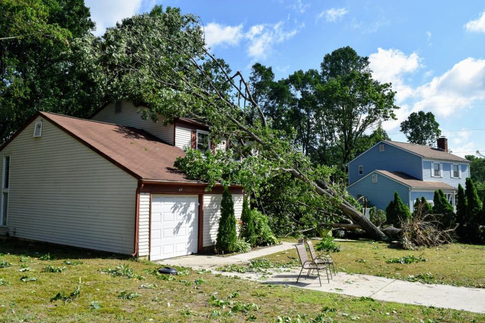 A fallen tree rests against a home in Gloucester Township, Camden County, after strong storms pushed through the area early Thursday morning.