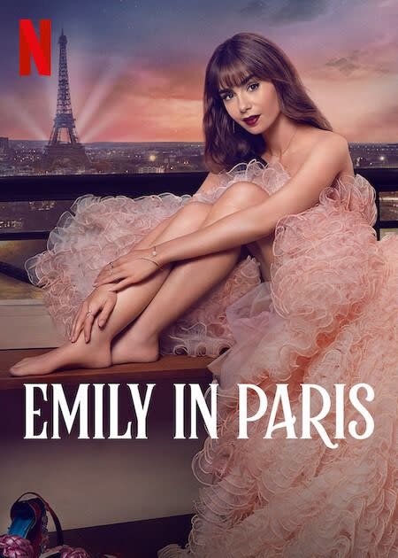 a brunette woman in a pink dress sitting on a balcony overlooking the eiffel tower