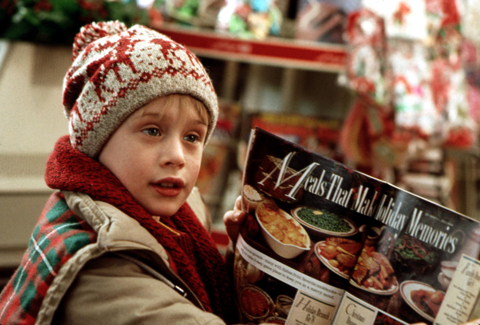 Macaulay Culkin as Kevin McCallister in a scene from "Home Alone," wearing a winter hat and holding a magazine