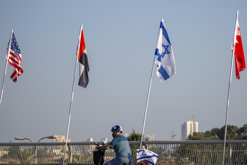 A man wearing a face mask against the coronavirus drives past flags, from left, of the United States, United Arab Emirates, Israel and Bahrain at the Peace Bridge in Netanya, Israel, Monday, Sept. 14, 2020. For the first time in more than a quarter-century, a U.S. president will host a signing ceremony between Israelis and Arabs at the White House, billing it as an "historic breakthrough" in a region long known for its stubborn conflicts. (AP Photo/Ariel Schalit)