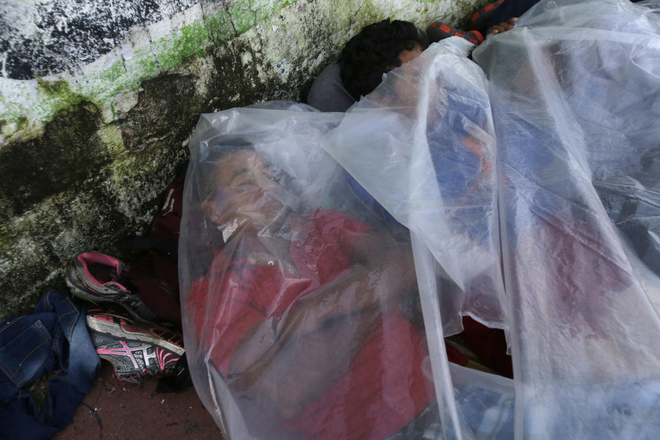 Central American migrants traveling with a caravan to the U.S., use a piece of plastic as covering as they sleep on a sidewalk in Huixtla, Mexico, Tuesday, Oct. 23, 2018. The caravan, estimated to include more than 7,000 people, had advanced but still faced more than 1,000 miles, and likely much further, to the end of the journey. (AP Photo/Moises Castillo)