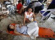 A woman comforts a pregnant relative having labour pains before she delivered a baby at a makeshift birthing clinic in typhoon battered Tacloban city in central Philippines November 11, 2013.