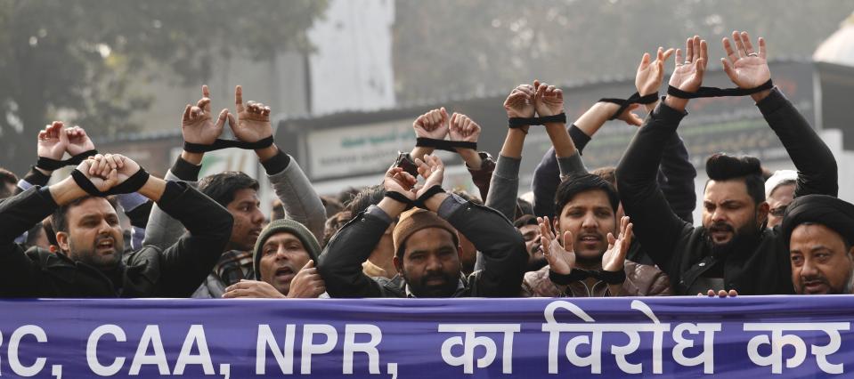 Indian raise their tied hands and shout slogans during a protest against the Citizenship Amendment Act in New Delhi, India, Friday, Dec. 27, 2019. Tens of thousands of protesters have taken to India's streets to call for the revocation of the law, which critics say is the latest effort by Narendra Modi's government to marginalize the country's 200 million Muslims. (AP Photo/Manish Swarup)