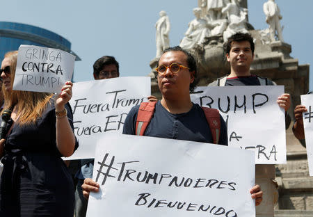 Demonstrators hold placards during a protest against the visit of Donald Trump, at the Angel of Independence monument in Mexico City. The placards read "Trump, you are not welcome," and "Trump out." REUTERS/Ginnette Riquelme