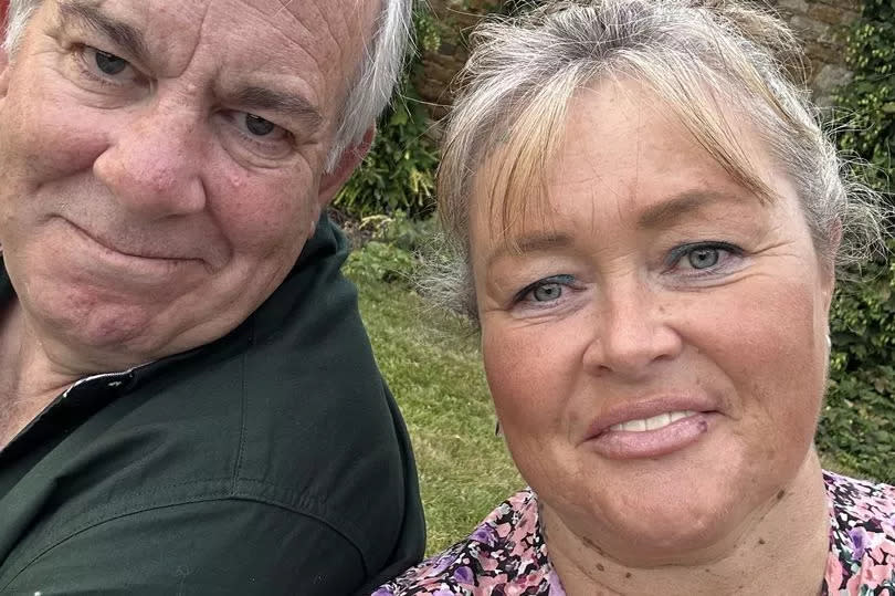 Melanie and Philip smiling at the camera in their garden