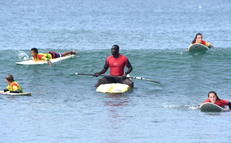 Senegalese surfer Oumar Seye (C) prepares for a wave with surf students on May 31,2015 on the Almadie beach in Dakar